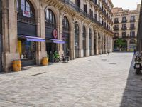 a cobblestone street in an european city on a sunny day with pedestrians on the sidewalk