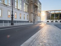 this is an image of a cobblestone street at sunset and street lamps on each side