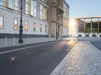 this is an image of a cobblestone street at sunset and street lamps on each side