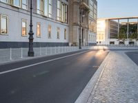 this is an image of a cobblestone street at sunset and street lamps on each side