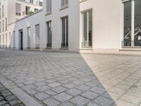 a woman riding her bike down an empty cobblestone street in the sunshine shine