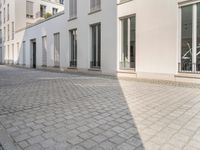 a woman riding her bike down an empty cobblestone street in the sunshine shine