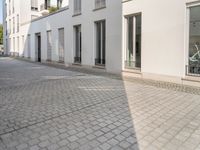 a woman riding her bike down an empty cobblestone street in the sunshine shine