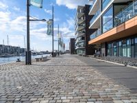 a cobblestone street leading down to a waterfront hotel complex with a bench sitting beside the building