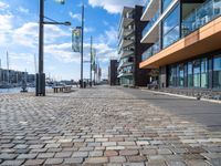 a cobblestone street leading down to a waterfront hotel complex with a bench sitting beside the building