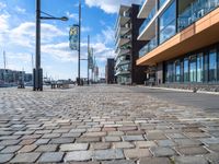 a cobblestone street leading down to a waterfront hotel complex with a bench sitting beside the building