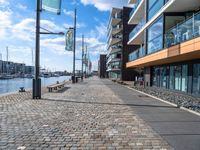 a cobblestone street leading down to a waterfront hotel complex with a bench sitting beside the building