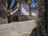 a cobblestone street in front of a wall and trees on both sides of it