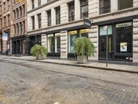 a cobblestone street and some buildings are shown at the intersection of two roads