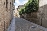 narrow cobblestone street in front of old buildings with a sky background with a sky line showing