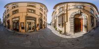 some people walk down a cobblestone street and are reflected in a spherical mirror