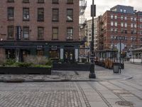 the sidewalk on a brick city street has many potted plants and small potted trees