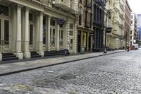 a person with an umbrella on a cobblestone street, in the city of new york