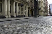 a person with an umbrella on a cobblestone street, in the city of new york