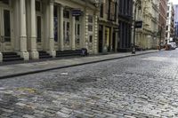 a person with an umbrella on a cobblestone street, in the city of new york