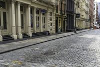 a person with an umbrella on a cobblestone street, in the city of new york