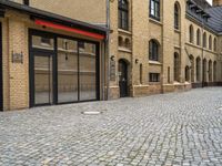 an outside city scene showing cobblestone and buildings with red trims that match