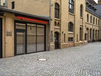 an outside city scene showing cobblestone and buildings with red trims that match