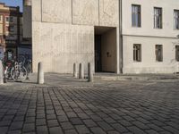 a person with a suitcase walking across an outside courtyard in front of a building,