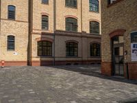 a sidewalk with chairs next to the brick building on the side, some have stairs and some buildings in the background