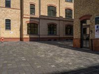 a sidewalk with chairs next to the brick building on the side, some have stairs and some buildings in the background