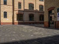 a sidewalk with chairs next to the brick building on the side, some have stairs and some buildings in the background