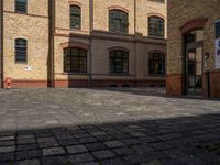 a sidewalk with chairs next to the brick building on the side, some have stairs and some buildings in the background