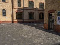 a sidewalk with chairs next to the brick building on the side, some have stairs and some buildings in the background