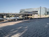 a brick courtyard with a bridge and walkway in the background that is next to a large building