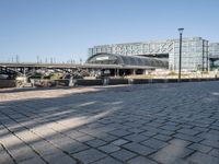 a brick courtyard with a bridge and walkway in the background that is next to a large building