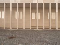 a room with columns near a building with light pouring through it and shadows in the windows