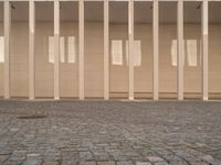 a room with columns near a building with light pouring through it and shadows in the windows