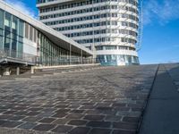 a person on a bike rides past an office building and stairs on a brick surface