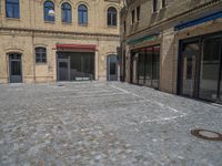 the sidewalk is paved with stones and has a bench in front of it, with no people inside