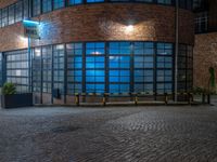 some dark blue windows in an industrial building with no one on the street to the right