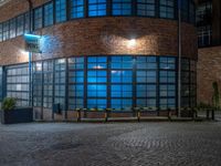 some dark blue windows in an industrial building with no one on the street to the right