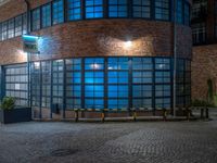 some dark blue windows in an industrial building with no one on the street to the right