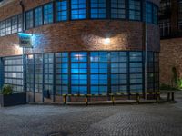 some dark blue windows in an industrial building with no one on the street to the right