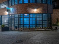 some dark blue windows in an industrial building with no one on the street to the right