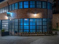 some dark blue windows in an industrial building with no one on the street to the right