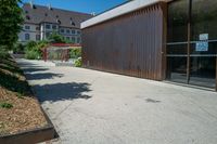 a skateboard ramp with a building in the background with a no parking sign hanging off it