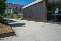 a skateboard ramp with a building in the background with a no parking sign hanging off it