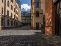 a sidewalk with chairs next to the brick building on the side, some have stairs and some buildings in the background