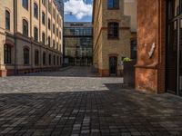 a sidewalk with chairs next to the brick building on the side, some have stairs and some buildings in the background