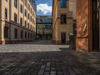 a sidewalk with chairs next to the brick building on the side, some have stairs and some buildings in the background