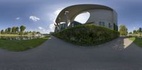 an art sculpture in a circular shape on the street beside the grass field and water