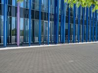 a building with pink glass and purple striped exterior is shown with the brick path on the left