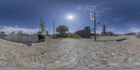 a fisheye view shows a cobblestone walkway next to a body of water