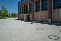 circles in the middle of the cement floor outside an empty building with a wooden facade