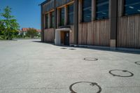 circles in the middle of the cement floor outside an empty building with a wooden facade